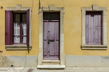Fototapeta na wymiar Yellow french house with red shutters at french small town southern France