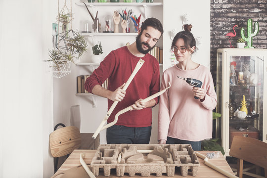 Young couple assembling flat-pack stool at home