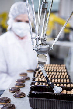 Woman in factory looking at robot handling cookies