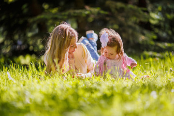 Family, mother and baby girl resting on nature, lying on grass
