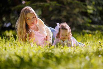 Family, mother and baby girl resting on nature, lying on grass

