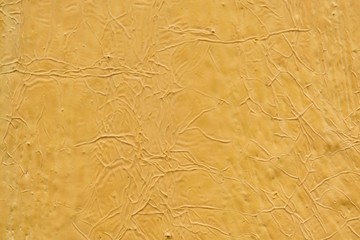 The texture of the walls of wood painted with yellow paint. Visible cracks, bumps and depressions.