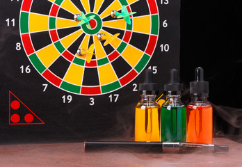 Electronic cigarette and bottles with vape liquid within vapor on dart board background