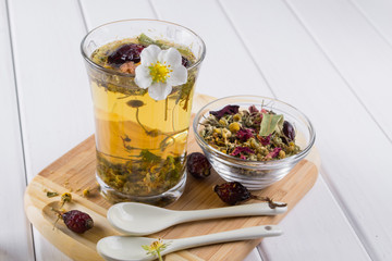 Herbal tea ingredients with hip roses, chamomile, herbs on white wooden table