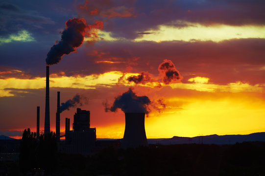 Coal power station in sunset with cloudy sky, industrial landscape