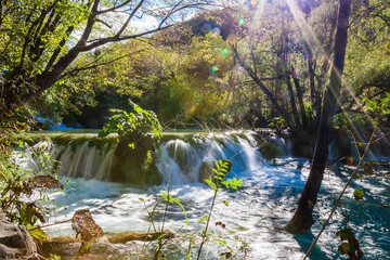 small waterfall with sunlight rays