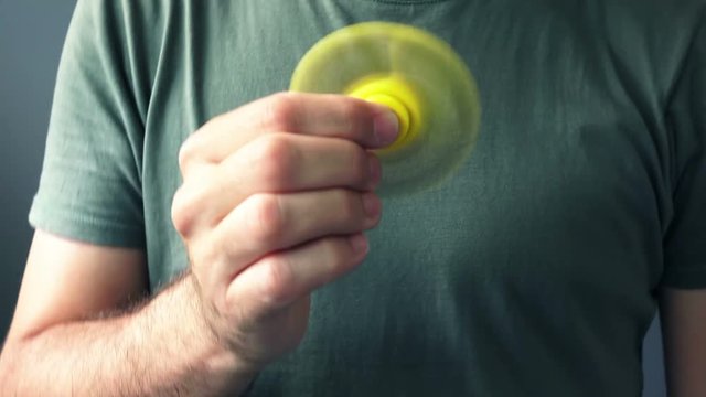 Man playing with yellow fidget spinner popular toy