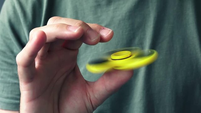 Man playing with yellow fidget spinner popular toy