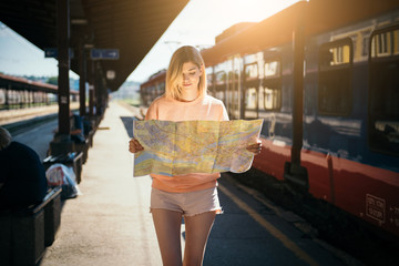 Young woman at the train station reading map  