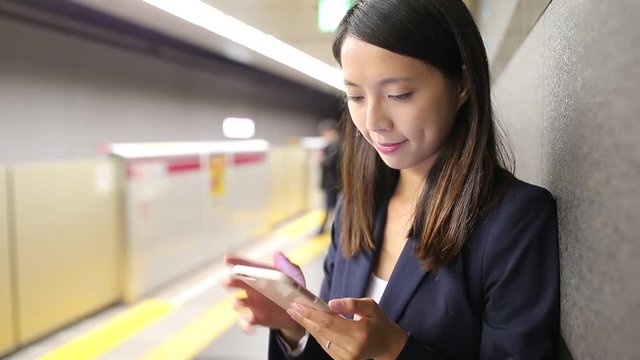 Businesswoman use of mobile phone in train station