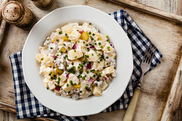 Traditional German potato salad with cucumber, onion and mayonnaise. Top view.