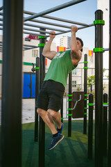 Handsome sexy male bodybuilder athlete man doing crossfit workout in athletic facilities on sunny morning outdoors. Healthy lifestyle concept. Physical preparation of body. pull-up on horizontal bar