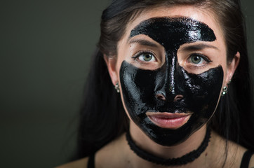 Close up of a beauty young woman using a black mask to clean skin