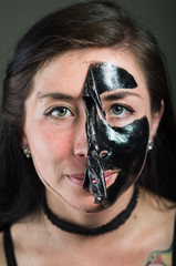Close up of a beauty young woman taking off half of a black face mask