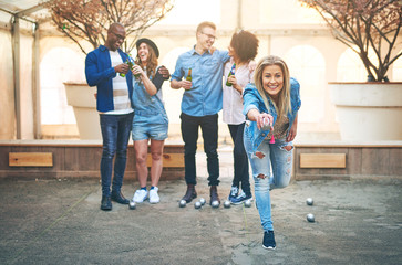 Drinking beer multiethnic friends playing petanque on court