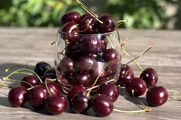 Fresh cherry in a glass on a wooden table.