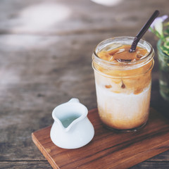 A glass of Iced coffee on wooden table in vintage cafe