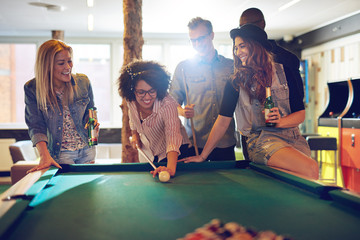 Woman behind the cue ball while friends watch - obrazy, fototapety, plakaty