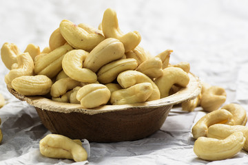 There is cashew wooden brown bowl which is been clciked on a white background.