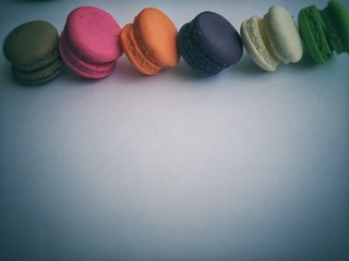 the colorful macaroons were stacked at the top of white background,in vintage design,pastel soft tone,blurry light around.
