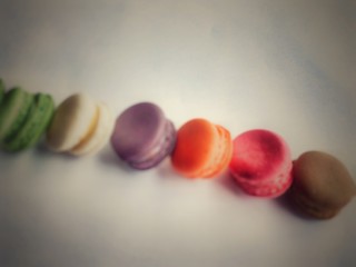the colorful macaroons stacked in row,in abstract design,glamour glow tone,pastel soft tone,vintage warm light tone,blurry around.