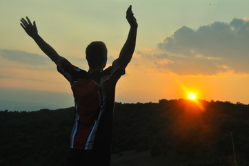 Fototapeta na wymiar The man raised his hands and enjoys in beautiful sunset. Concept of happiness and summer vacations
