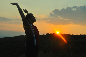 The man raised his hands and enjoys in beautiful sunset. Concept of happiness and summer vacations