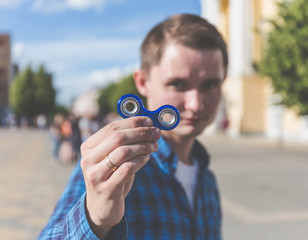Young hipster man showing to camera fidget spinner