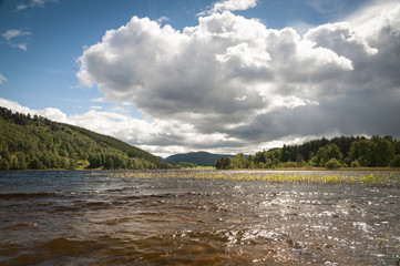 Fototapeta na wymiar Summer clouds and sunlight across Loch Pityoulish near the Cairngorms in Badenoch and Strathspey, Scotland