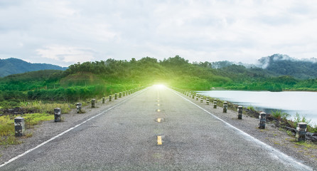 Fototapeta premium Goals or Finishes Line Concept. Perspective View of Asphalt Road Between Forests and Rivers to Mountain with Trees and Cloudy Sky in Summer Season, Thailand as Copyspace to mock up or input text