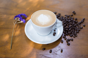 Coffee cup and coffee beans on table on a wooden desk