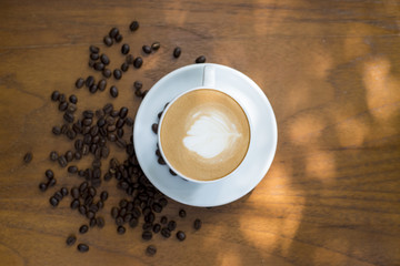 Coffee cup and coffee beans on table on a wooden desk