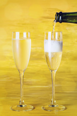 Champagne poured into glasses on golden background