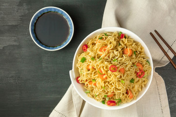 Instant noodles with vegetables, sauce, chopsticks, copy space