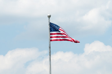 Flag of the United States of America with blue sky and clouds behind it