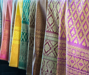 Beautiful Row of Traditional Colorful Thai Silk Fabric Textile with Seamless Pattern of Vintage Thai Design Style hanging in The Fashion Store for Sell used as Template