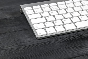 Close up view of a workplace with wireless computer keyboard, keys on old black wooden table background