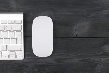 Close up view of a business workplace with wireless computer keyboard, mouse and keys on old black wooden table background