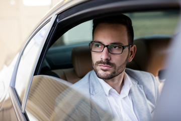 Confident and serious young businessman traveling inside his car.