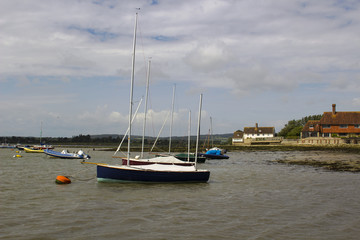 Fototapeta na wymiar Pleasure boats on their moorings in the historic Bosham Harbour in West Sussex in the South of England