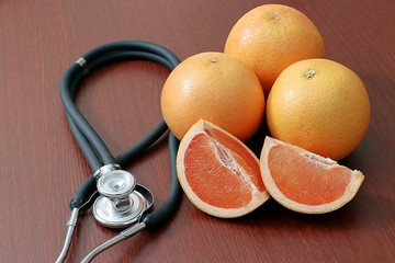 partial view of coiled stethoscope next to fresh grapefruit