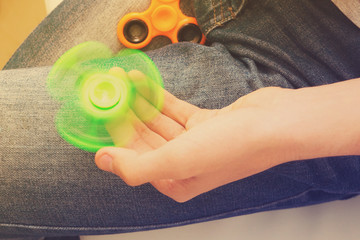 trendy fidget spinner - person holding spinning green fidget spinner in hand, close up view, retro...