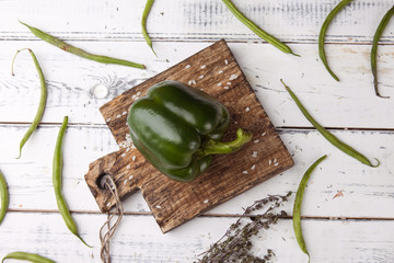 Green bell pepper on wooden cutting plank.