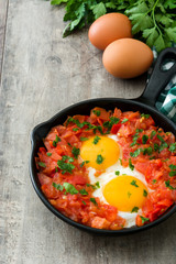 Shakshuka in iron frying pan on wooden table. Typical food in Israel.
