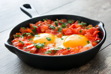 Shakshuka in iron frying pan on wooden table. Typical food in Israel.
