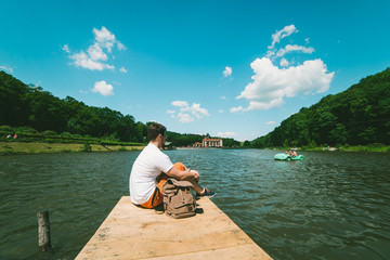 Man sitting on a lake pier