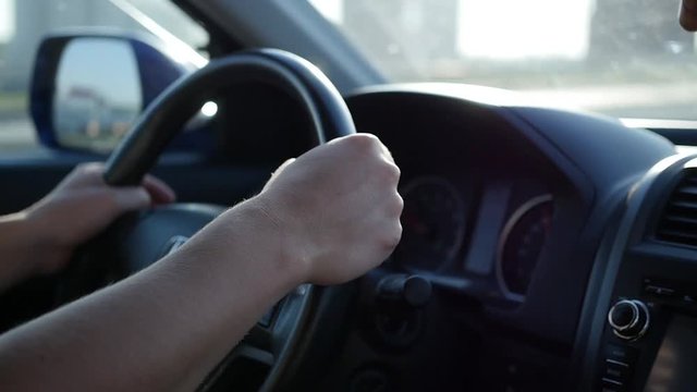 the guy drives a car on a Sunny day. The time of sunset. Hands and steering wheel closeup