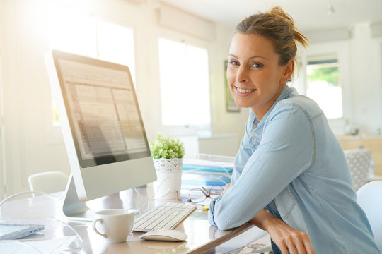 Beautiful young woman in office working on desktop computer