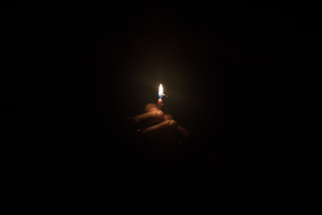 Hand holding burning candle in the dark - obrazy, fototapety, plakaty
