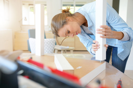 Woman doing DIY work, assembling furniture at home